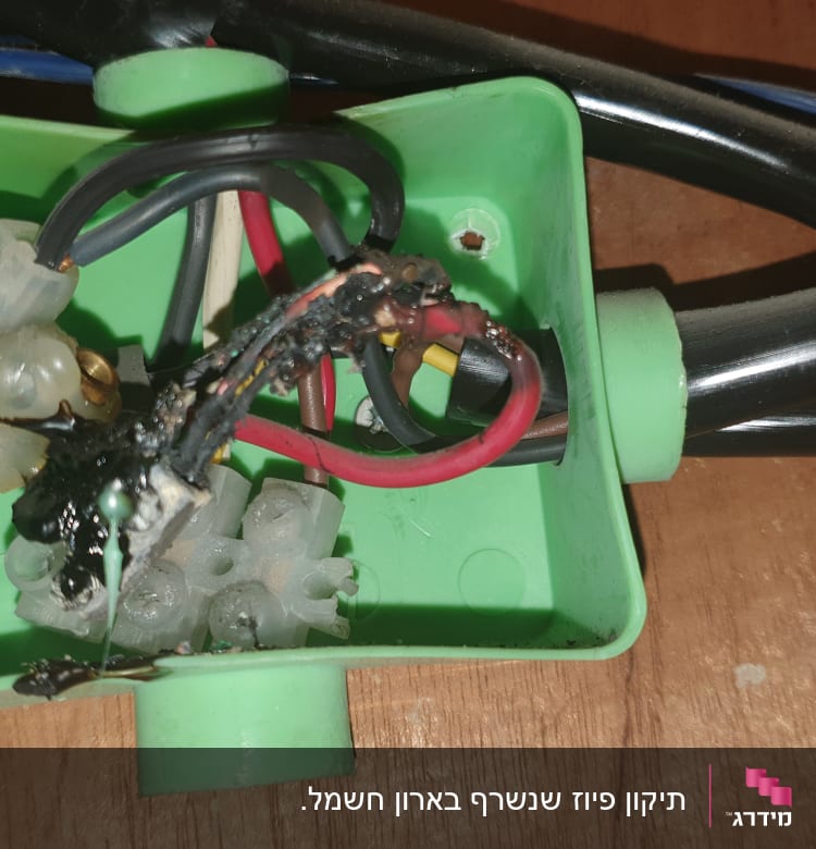 חוטי חשמל שרופים בתוך קופסת חיבורים ירוקה